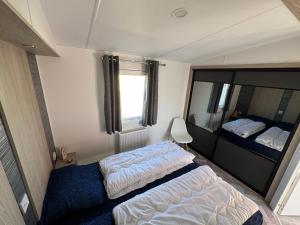 a small bedroom with two beds and a mirror at Chalet 82 in Petten