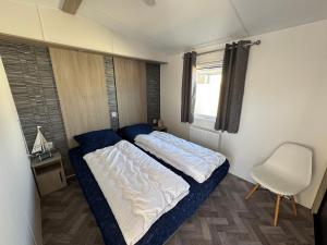 a bedroom with a bed and a chair in it at Chalet 82 in Petten +11 photos