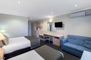 pokój hotelowy z łóżkiem i niebieską kanapą w obiekcie Adelaide Granada Motor Inn w mieście Adelaide