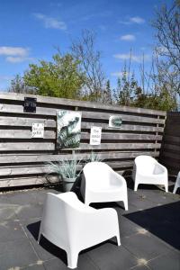 Eine Gruppe weißer Stühle steht auf einer Terrasse in der Unterkunft J 071 in Petten