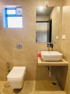 a bathroom with a toilet and a sink and a mirror at SHARDUL HERITAGE THE RESORT in Mahabaleshwar