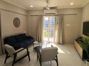 a living room with a blue couch and a table at Treat Homes Service Apartment in BKC Siddhant 401 in Mumbai