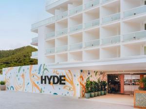 un grand bâtiment blanc avec un panneau de randonnée. dans l'établissement Hyde Ibiza, à Cala Llonga