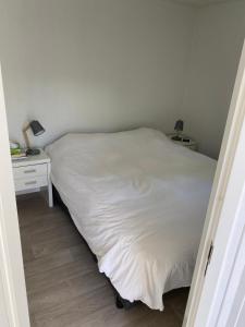 ein Schlafzimmer mit einem Bett und einem Nachttisch mit einer weißen Tagesdecke in der Unterkunft J121 in Petten
