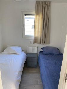 zwei Betten in einem kleinen Zimmer mit Fenster in der Unterkunft J121 in Petten