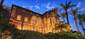 a large brick building with palm trees in front of it at The Scots Hotel in Tiberias