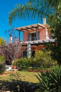 une maison rose au milieu d'un jardin dans l'établissement The Moon House, à Prévéza