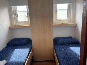 zwei Betten in einem kleinen Zimmer mit zwei Fenstern in der Unterkunft J 134 in Petten