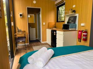 ein Schlafzimmer mit einem Bett und eine Küche mit Handtüchern in der Unterkunft Tranquility Ranch by Tiny Away in Wolfdene