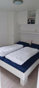 ein Bett mit weißen Laken und einer blauen Matratze in der Unterkunft J 174 in Petten