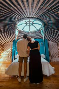 a man and a woman kissing in front of a bed at Glamping El Jardín De Las Delizias Valle Del Jerte in Casas del Castañar +120 photos