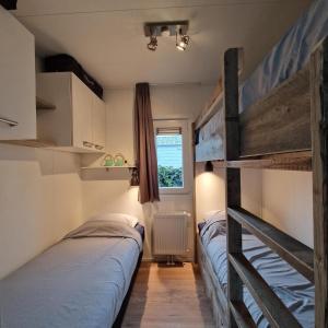 two bunk beds in a room with a window at Chalet 216 in Petten