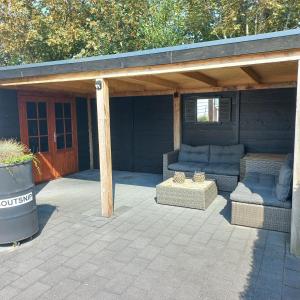 eine überdachte Terrasse mit Sofa und Tisch in der Unterkunft J 217 in Petten