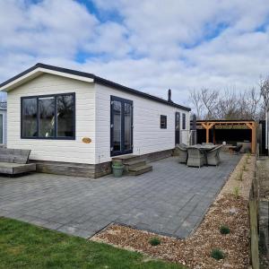 a white house with a patio and a patio table at Chalet 216 in Petten
