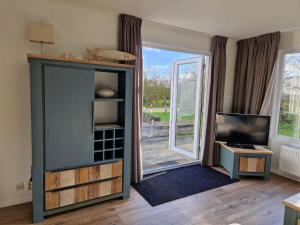 ein Wohnzimmer mit Fernseher und einer großen Glasschiebetür in der Unterkunft J 216 in Petten