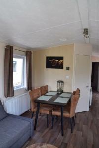 a living room with a table and chairs and a couch at Chalet 217 in Petten +7 photos