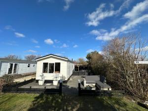 a white house with a porch and a yard at Chalet 218 in Petten