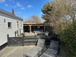 a patio with tables and benches next to a building at Chalet 218 in Petten