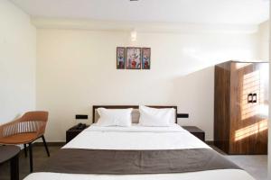 a bedroom with a large bed and a chair at Townhouse Oak NFC Crossway Hyderabad in Maula Ali