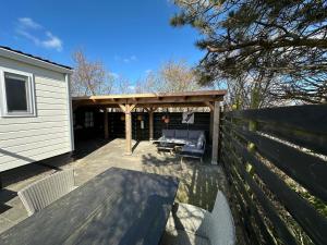 a wooden pergola with a couch on a patio at Chalet 218 in Petten