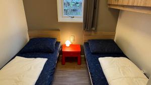 ein kleines Zimmer mit zwei Betten und einem roten Tisch in der Unterkunft J 106 in Petten