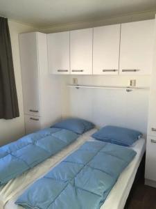 zwei Betten in einem Zimmer mit weißen Schränken und blauen Kissen in der Unterkunft J 228 in Petten + 7 Fotos