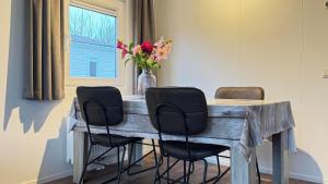 ein Esstisch mit vier Stühlen und einer Blumenvase in der Unterkunft J 228 in Petten