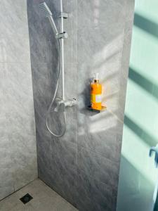 a shower in a bathroom with a yellow bottle on a shelf at Luna Apartment in Dodoma