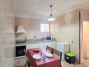 Una cocina con una mesa con mantel rojo y sillas. en Emelina, en La Guancha