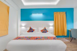 a bedroom with a large white bed with blue walls at FabHotel SLR Residency - AECS Layout, Brookefield in Bengaluru