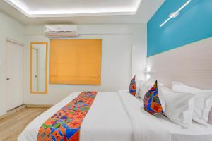 a bedroom with a large white bed with colorful pillows at FabHotel SLR Residency in Bengaluru