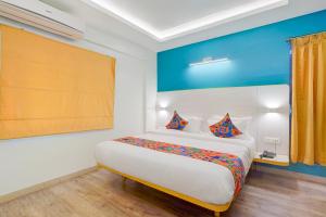 a bedroom with a large bed with a blue wall at FabHotel SLR Residency - AECS Layout, Brookefield in Bengaluru