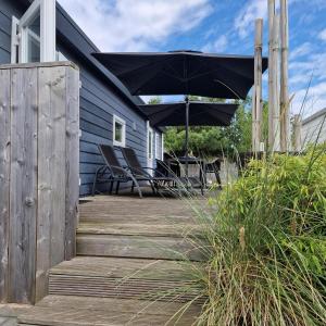 eine Terrasse mit einem schwarzen Sonnenschirm und Stühlen auf einem Haus in der Unterkunft J 231 in Petten