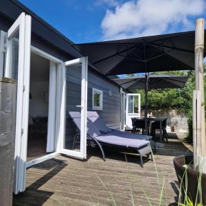 patio con ombrellone, panca e tavolo di Chalet 231 a Petten Altre 7 foto