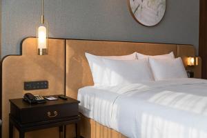 a bedroom with a white bed with a night stand with a clock at Guangzhou Dong Fang Hotel in Guangzhou