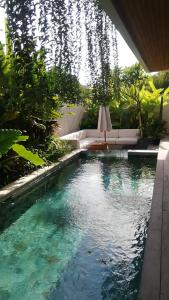 a pool in a garden with a table and chairs at Sagrada Villa Canggu Bali in Dalung