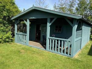 a blue shed with a porch on the grass at Kampeerhut in Petten