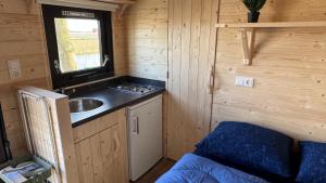 a small kitchen with a sink in a wooden cabin at Campervan in Petten