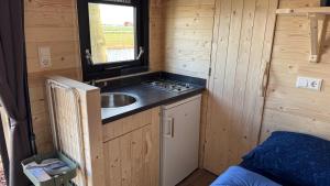 a kitchen with a sink in a tiny house at Kampeerwagon in Petten +8 photos