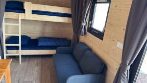 a living room with a couch and bunk beds at Kampeerwagon in Petten