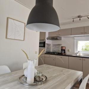 una cucina con un tavolo con una lampada nera di Chalet 231 a Petten