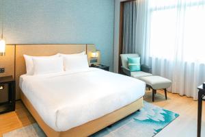 a bedroom with a large white bed and a chair at Guangzhou Dong Fang Hotel in Guangzhou
