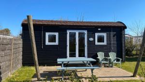 a small black shack with a picnic table and two chairs at Kampeerwagon in Petten