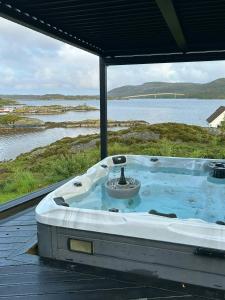 a jacuzzi tub sitting on a deck next to the water at Cabin With Sea Views In Mjømna 