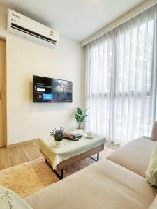a living room with a couch and a tv on the wall at BangTao Rooftop Seaview Laguna Skypark Condominium in Laguna Phuket
