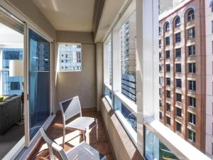 a balcony with a chair and two windows at Mantra on Kent in Sydney