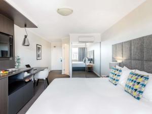 a hotel room with a large white bed and a desk at Mantra on Northbourne in Canberra