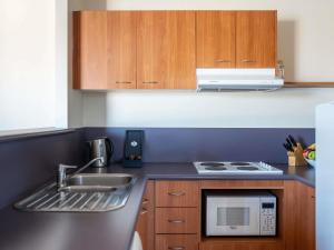 a kitchen with a sink and a microwave at Mantra on Northbourne in Canberra