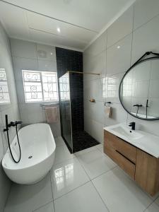 a white bathroom with a sink and a shower at 10 on Pauling Hotel Bulawayo in Bulawayo