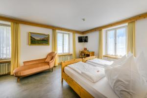ein Schlafzimmer mit zwei Betten, einem Stuhl und Fenstern in der Unterkunft Hotel Suisse, Swiss Alpine Charm in Poschiavo